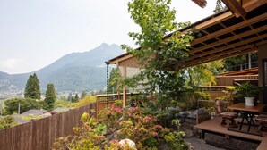 A patio with a wooden table and chairs, surrounded by a wooden fence and lush greenery. - Yufuin Sanso Waremokou (Yufu)
