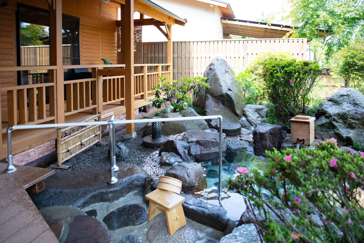 A wooden deck with a stone pathway leading to a small wooden bench and a rock garden.