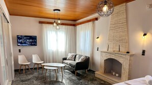 Una habitación de hotel moderna con chimenea, un sofá, un televisor y una cama.