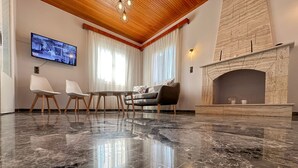Una habitación amplia con piso de mármol, chimenea, televisor y mobiliario.