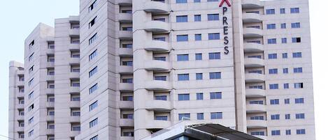 A multi-story hotel with a prominent 'X' sign on the side, indicating a specific area or feature.