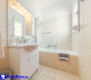 Een bad/douchecombinatie, een haardroger, handdoeken, toiletpapier