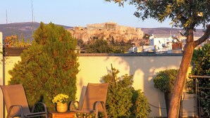 Una terrazza con due sedie e un tavolo, con vista su antiche rovine.