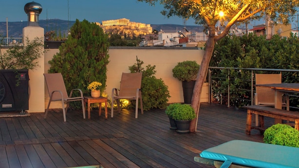 Una terrazza sul tetto con piscina, poltrone prendisole, un tavolo e piante in vaso.