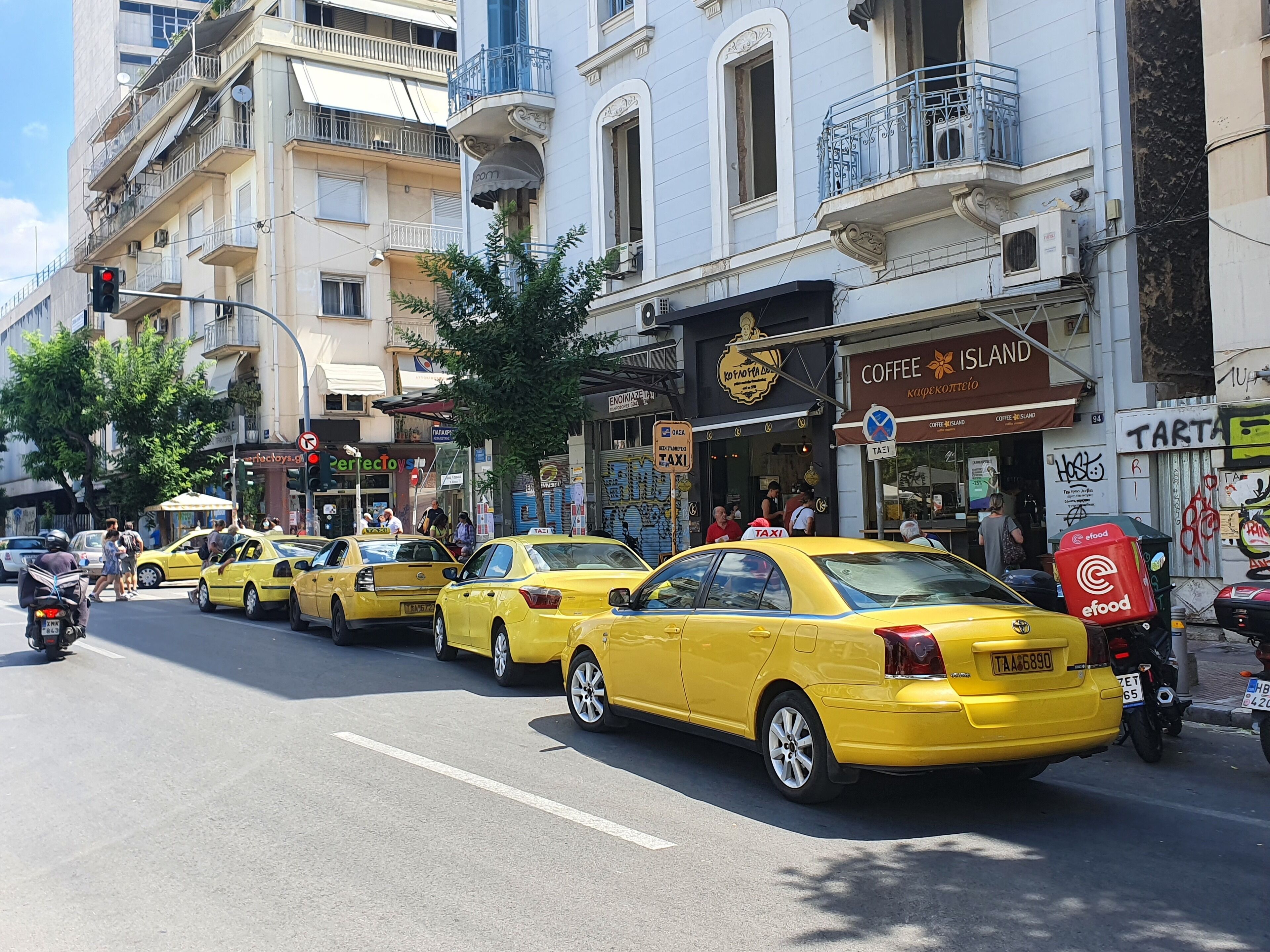 Une rue bordée de taxis jaunes, un café et diverses boutiques.