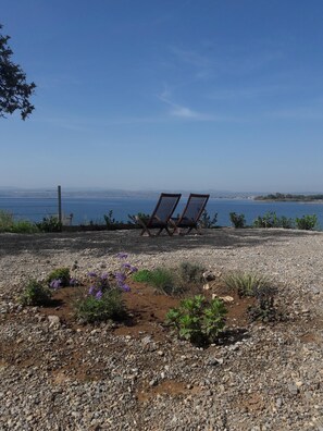 Relax in a serene outdoor seating area with two lounge chairs overlooking a tranquil body of water.