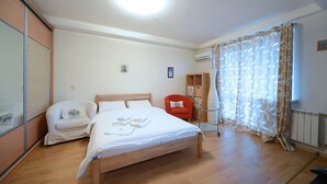 A bedroom with a wooden bed, a red chair, a white sofa, and a glass partition.