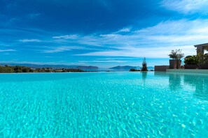 Piscina azul cristalina con vistas a montañas lejanas y un cielo despejado.