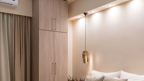 Camera da letto moderna con un letto in legno, pareti color beige, un condizionatore d'aria a soffitto e una lampada a sospensione.