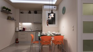 Una cucina moderna con mobili bianchi, un tavolo da pranzo con sedie arancioni e una lampada a sospensione.