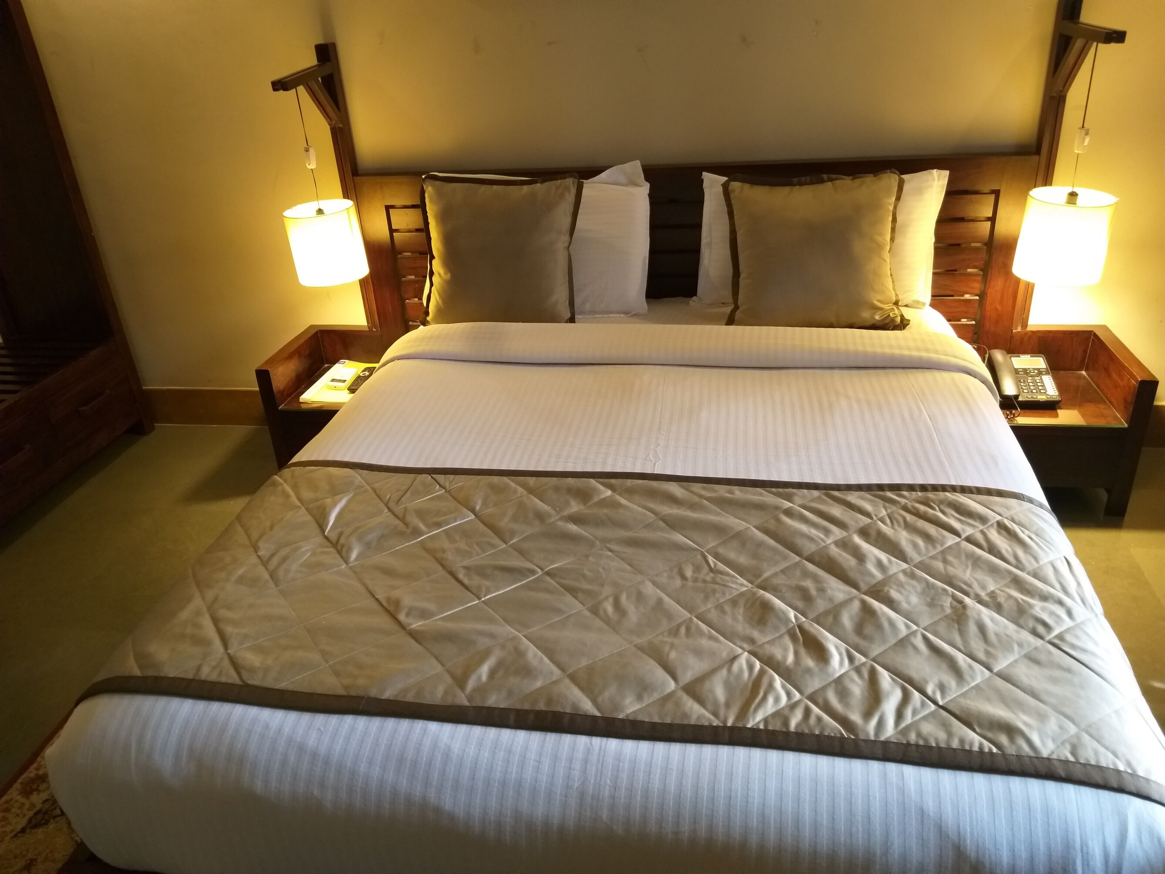 A hotel room with a large bed, two bedside tables with lamps, and a wooden headboard.