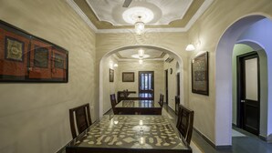 Un comedor con una mesa de vidrio, sillas y una lámpara de araña.