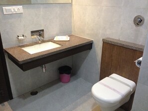 A bathroom with a sink, toilet, and a trash bin. - Hotel Plaza Inn Ajmer (Ajmer)