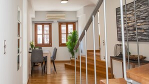 A modern interior with a dining area, staircase, and artwork. - Agora Suites  - Stay in the HEART of CHANIA (Χανιά)