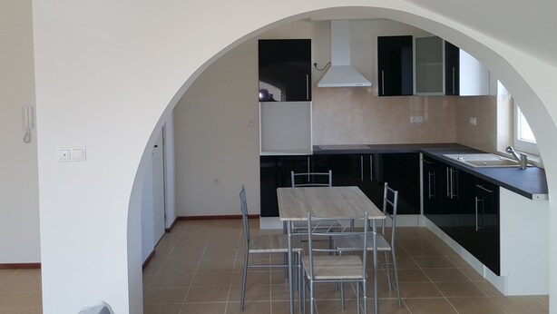 A modern kitchen with an arched ceiling, a dining table with chairs, and a built-in oven. - Apartmány Horná Seč (Horná Sec)