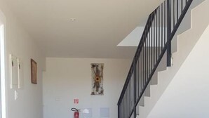 A spacious hallway with a staircase on the right, a fire extinguisher on the wall, and a door on the left. - Apartmány Horná Seč (Horná Sec)