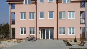 A multi-story residential building with a central entrance, balconies, and a paved driveway. - Apartmány Horná Seč (Horná Sec)
