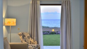Une pièce avec vue sur la mer, un fauteuil à motifs, une lampe et une table sur laquelle se trouve un chat.