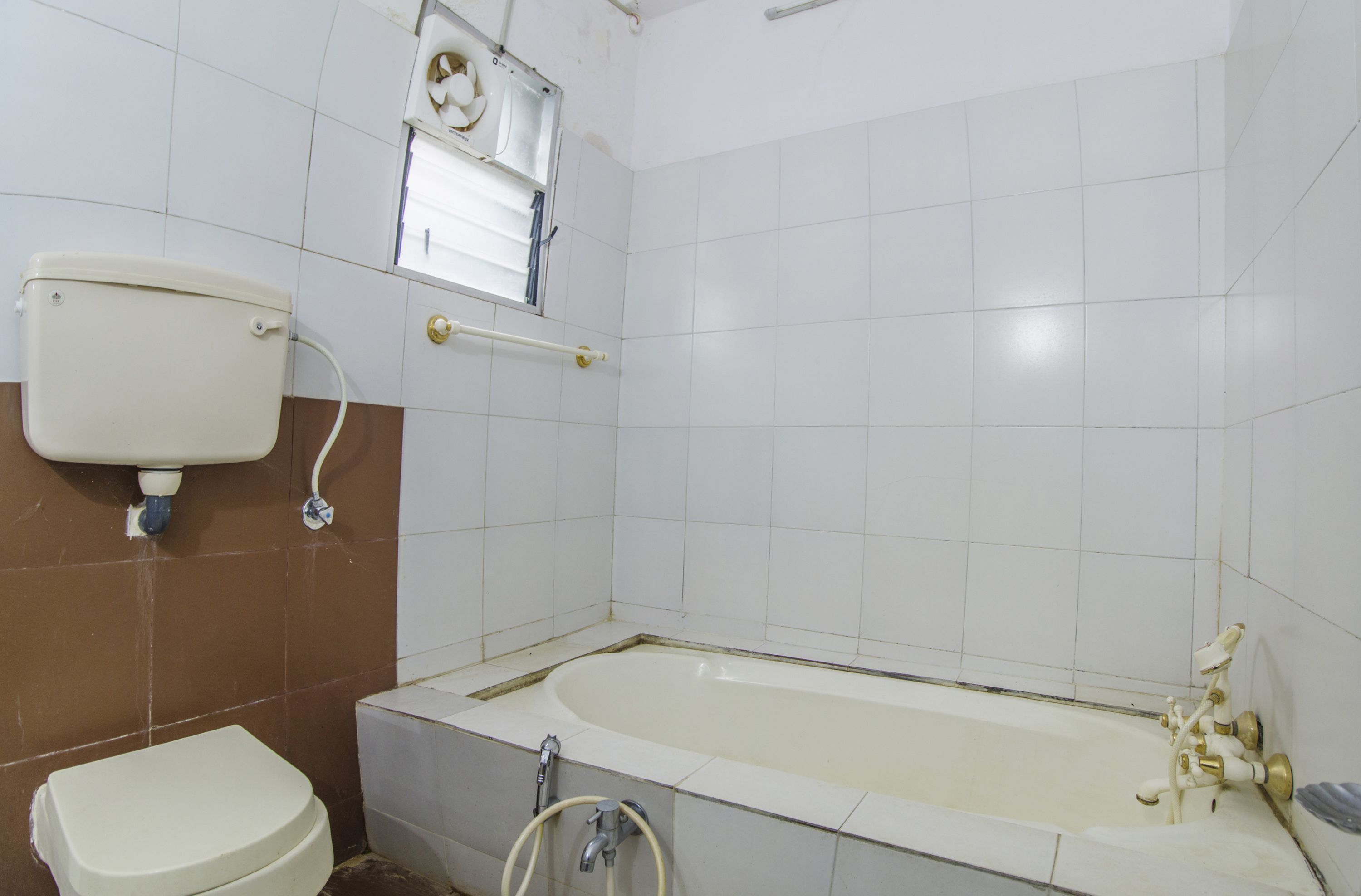 A bathroom with a toilet, a bathtub, and a window.