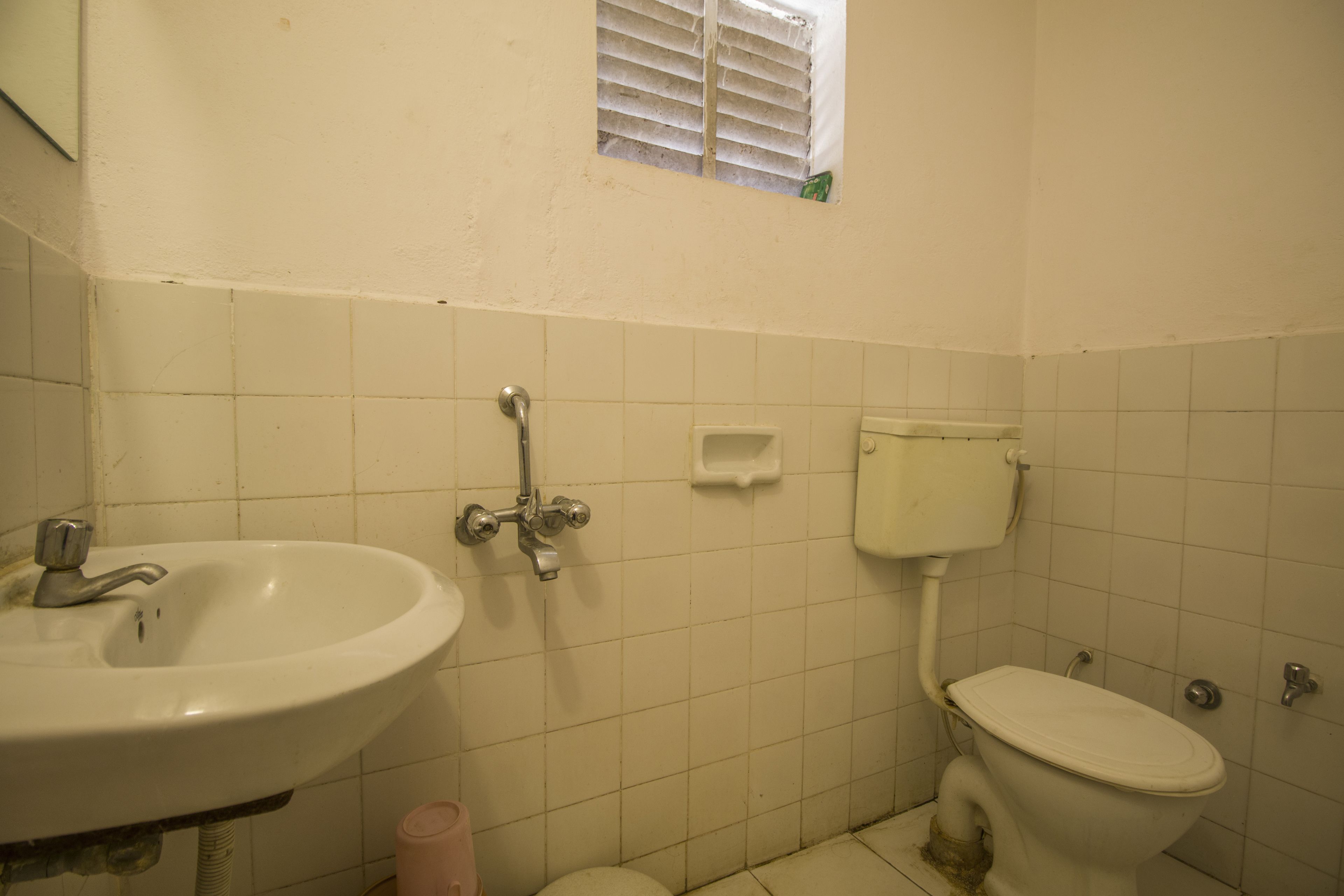 Un baño pequeño con lavamanos, inodoro y ventana.
