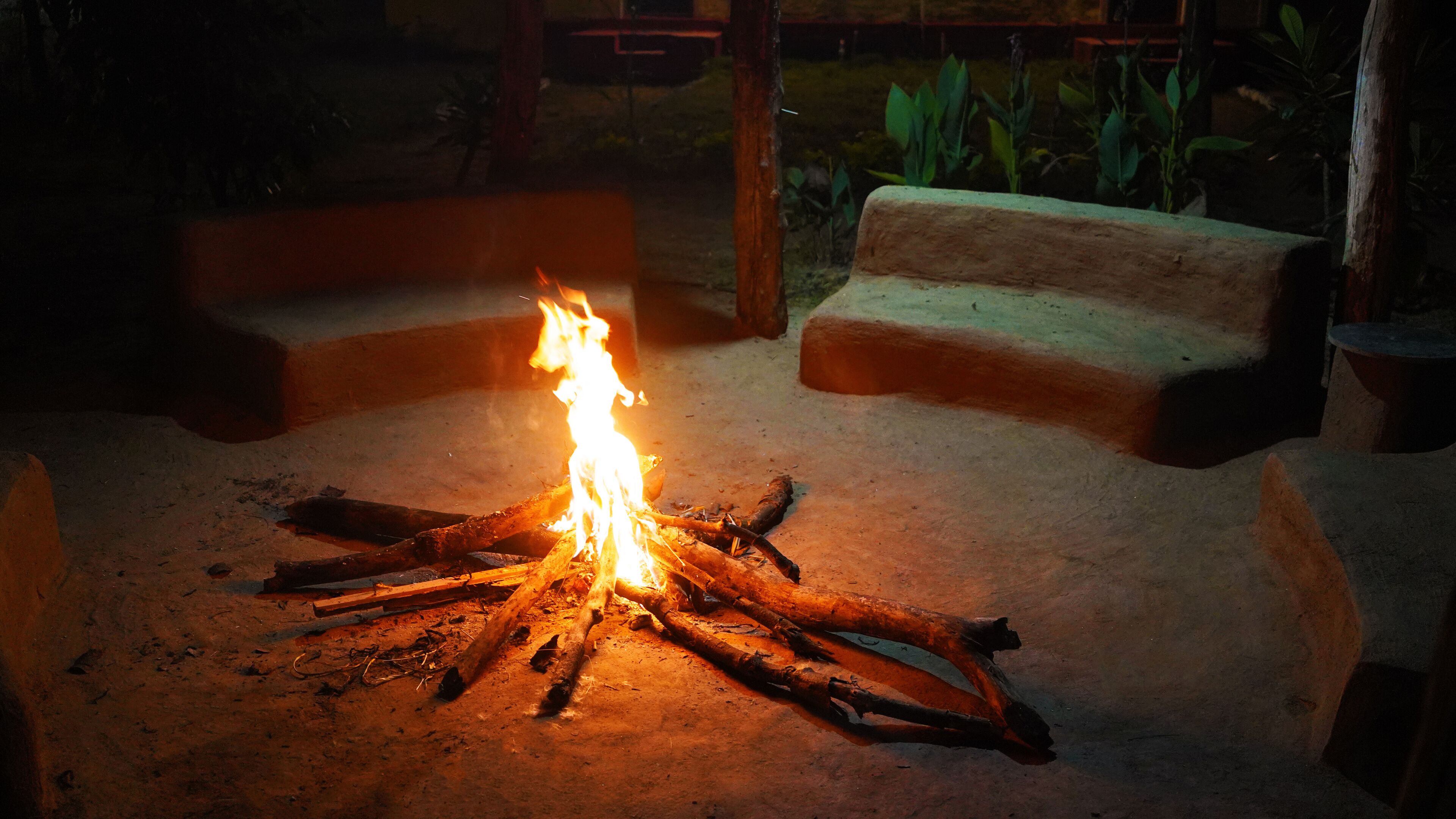 A campfire with logs arranged in a circle, surrounded by a stone seating area.