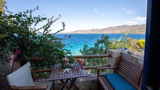 A wooden bench and table with a starfish decoration, overlooking a coastal view with clear blue sea and distant hills. - Villa Fea - Beach Front Secluded luxury residence with spectacular sea views (Πέρδικα)