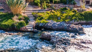 A coastal property with a rocky shoreline, a staircase leading to a building with a red-tiled roof, and lush greenery. - Villa Fea - Beach Front Secluded luxury residence with spectacular sea views (Πέρδικα)
