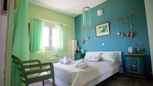 A bedroom with a bed, a chair, a bedside table, a nightstand, and a wall with decorative items. - Villa Fea - Beach Front Secluded luxury residence with spectacular sea views (Πέρδικα)