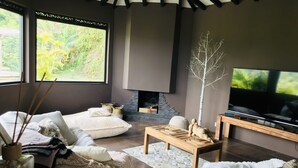 Un salon moderne avec une cheminée, un grand téléviseur et des sièges confortables.