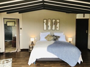 A bedroom with a bed, two bedside lamps, a large window, and a door. - Te Fiti Island Break Mahina (Mahina)