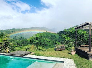 A pool area with a view of a lush landscape and a rainbow in the distance. - Te Fiti Island Break Mahina (Mahina)