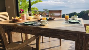 Une table de petit-déjeuner dressée avec des assiettes, des tasses et un saladier rempli de fruits, offrant une vue panoramique.