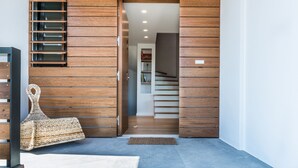 Une entrée moderne avec des lambris en bois, un banc en osier et un escalier menant à un niveau supérieur.