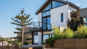 Une maison moderne à deux étages, dotée d’un balcon, d’une piscine et d’un jardin.
