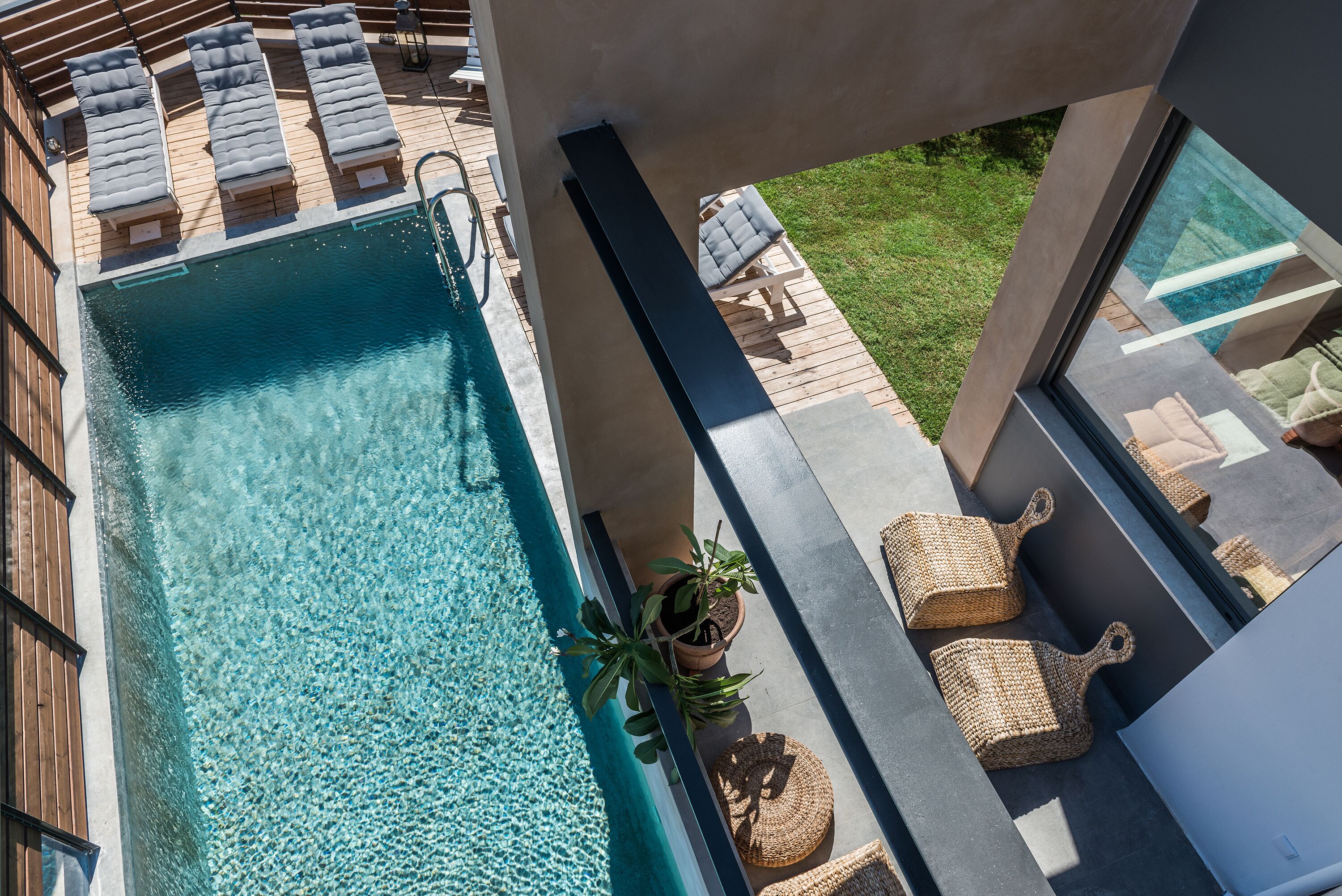 A rooftop pool area with lounge chairs, a potted plant, and wicker baskets.