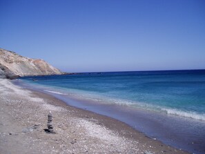 Une plage à l’eau d’un bleu limpide et au rivage rocheux.