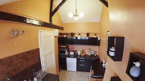A compact kitchen with a built-in dishwasher, a sink, and a small dining area with a chair.