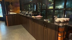 A kitchen area with a long counter, various kitchen utensils, and a brick wall. - JW Heritage (Anjuna)