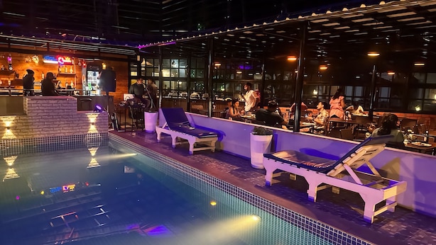 A rooftop pool area with lounge chairs and a bar. - JW Heritage (Anjuna)