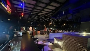An indoor restaurant with a checkered floor, a bar area, and a stone wall feature. - JW Heritage (Anjuna)