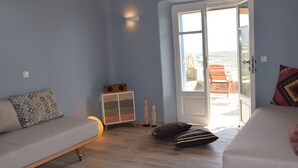 Een kamer met een bank, een kast met een kleurrijk ontwerp, en een deur naar een buitenruimte met een stoel.
