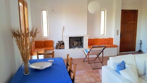 A dining area with a blue tablecloth, a vase with dried plants, and a fireplace.