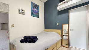 A bedroom with a bed, a poster on the wall, a wardrobe, and a door. - Home WIFI & Compact & Tranquil Apt with LOFT! (杉並区)