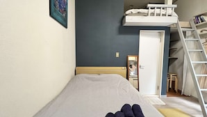A bedroom with a bunk bed, a bed with a striped bedspread, a small bedside table, a mirror, and a ladder leading to the bunk bed. - Home WIFI & Compact & Tranquil Apt with LOFT! (杉並区)