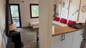 A room with a bed, a bench, a table with a tray, and a wall with decorative plates. - Beachfront family house (Ουρανούπολη)