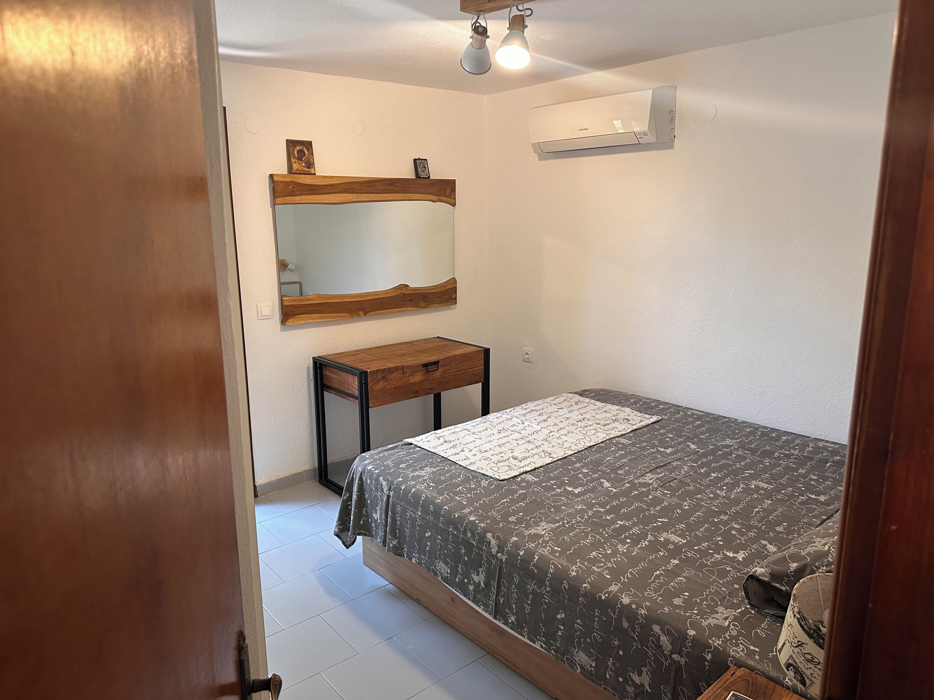 Una camera da letto con un letto, un comodino, uno specchio e un condizionatore d'aria.