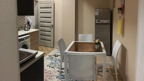 Una cucina funzionale con tavolo e sedie, una lavatrice, un frigorifero e una porta con maniglia.