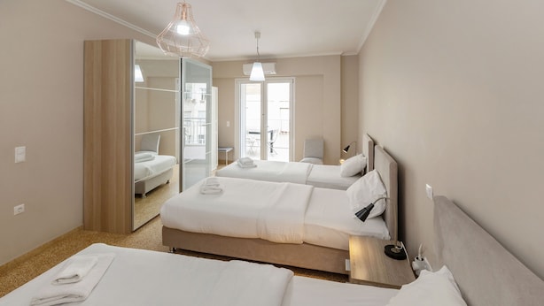 A hotel room with two beds, a large mirror, a ceiling light, and a view of the balcony. - Leonidas Loft in the Heart of Athens by GHH (Athens)
