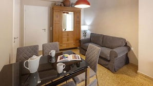 A living room with a sofa, a dining table with chairs, a coffee table, a book, a teapot, and a lamp. - Leonidas Loft in the Heart of Athens by GHH (Athens)