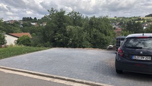 Ein gepflasterter Weg führt zu einem abgestellten Auto.